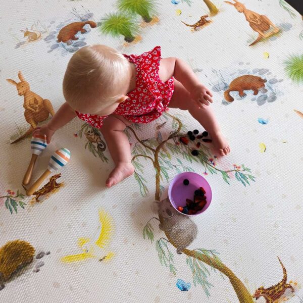 A baby is playing on the playmat