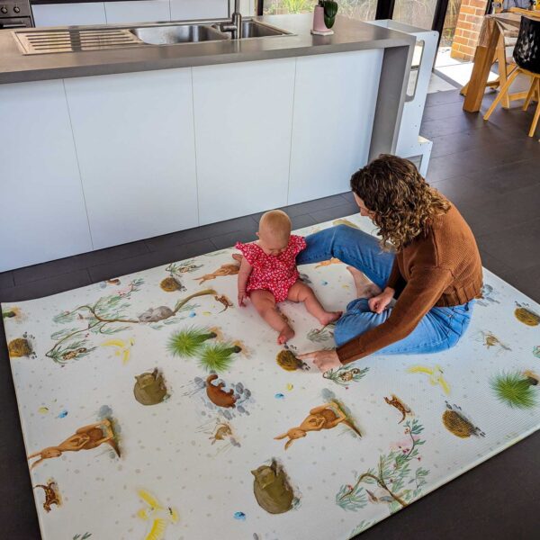 A mother and a baby are sitting on the playmat